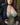 Person wearing a black jacket over a lace top with a blurred background