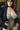 Person wearing a black jacket over a lace top with a blurred background