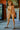 Naked person standing indoors with a painting in the background