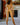 Naked person standing in a room with a fireplace and painting on the wall.