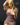 A highly realistic beige sex doll with long blonde hair, posed in a pink dress.