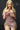 A highly realistic beige sex doll with long blonde hair, posed in a pink dress.