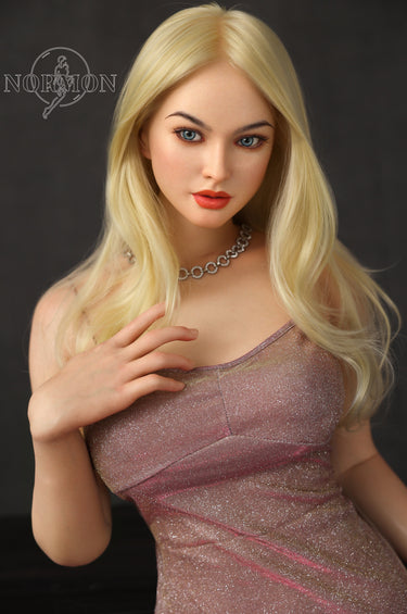 A highly realistic beige sex doll with long blonde hair, posed in a pink dress. The doll has a lifelike appearance with detailed facial features and a flexible skeleton, designed for versatile posing.