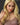Close up of A highly realistic beige sex doll with long blonde hair, posed in a pink dress.