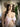 The image shows a highly realistic sex doll with long brown hair, wearing a pink lacey white top and a brown hat. The doll has a lifelike appearance with detailed facial features and is posed in a manner that highlights her natural curves.