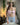 The image shows a highly realistic sex doll with long brown hair, wearing a pink lacey white top and a brown hat. The doll has a lifelike appearance with detailed facial features and is posed in a manner that highlights her natural curves.