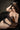 A realistic silicone doll with long brown hair, wearing a black lace bra and panties, sitting on a chair.