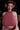 Person wearing a pink halter top and headphones in a dimly lit room.