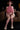 Person wearing a pink outfit with matching headphones sitting on a brown couch.