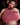 Person wearing a pink top with exaggerated cleavage in a dark setting