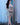 Woman in a silver dress standing in a room with curtains and a white rug.