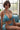 Woman in a blue bikini sitting on a couch with a blurred background