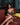 Woman in a gold dress sitting on a red couch with a blurred background