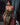 Woman in a gold and black patterned dress standing indoors with a blurred background