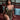 Woman in a gold dress sitting on a red couch with a blurred background