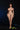 Naked woman standing against a black background with a green object on the ground.