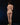 Naked person standing on a black background with green leaves on the ground.