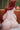 Person with red hair sitting on a couch in a room with a lamp and curtains.