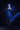Person in a blue dress with long hair and black gloves against a dark background