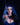Person with blue hair and horns wearing a blue dress against a black background