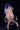 Statue of a nude figure with blue hair sitting on a chair against a black background
