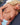 Realistic silicone doll with blonde hair and blue eyes lying on a blue cushion.