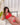 Person wearing a red lingerie set on a white couch with plants and curtains in the background.