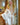 Sex doll wearing a white satin robe in a wooden room.