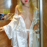 Sex doll wearing a white satin robe in a wooden room.