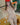 Sexualized figure holding a baseball bat and ball on a wooden surface.
