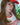 Person wearing a red cap and 'Boston 1998' shirt with blurred greenery in the background