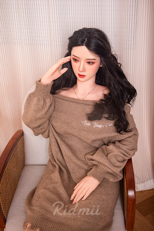 Person wearing a brown sweater with 'Ridmii' branding, sitting on a chair.