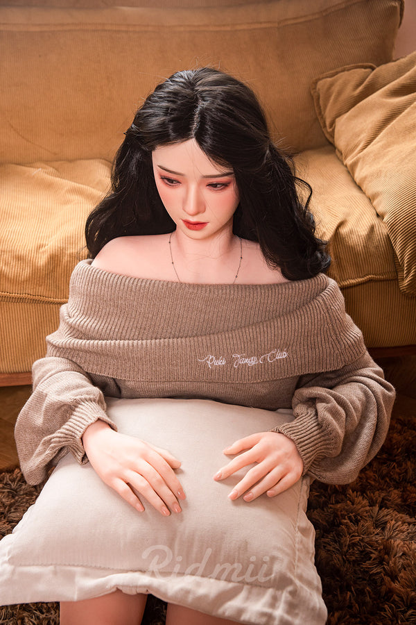Person wearing a beige sweater with text sitting on a brown couch.