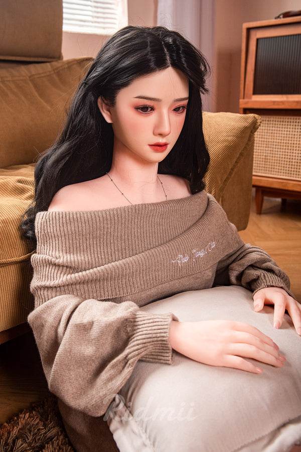 Person wearing a brown sweater sitting on a couch in a living room.