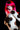 Person with bright pink hair and polka dot outfit against a black background