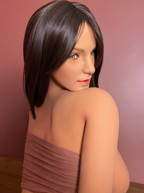 Woman with short dark hair wearing a brown dress against a pink background