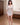 Woman in a white nightgown standing in a bedroom.