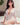 Woman in a white outfit sitting on a bed with a neutral background