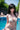Person in a white bikini by a pool with greenery in the background