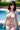 Woman in a bikini standing by a pool with greenery in the background