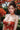 Woman in a traditional red dress with floral patterns standing in a garden with flowers and greenery.