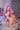 Sex doll with pink hair sitting on a chair in a room with a poster and decor.
