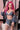 Person with pink hair wearing a denim outfit holding a book.