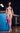 Naked person standing in a room with blue tiled walls and a bar stool.