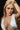 Woman with long blonde hair and a white top against a dark background