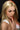 Woman with blonde hair and a white top, posing with a finger to her lips.