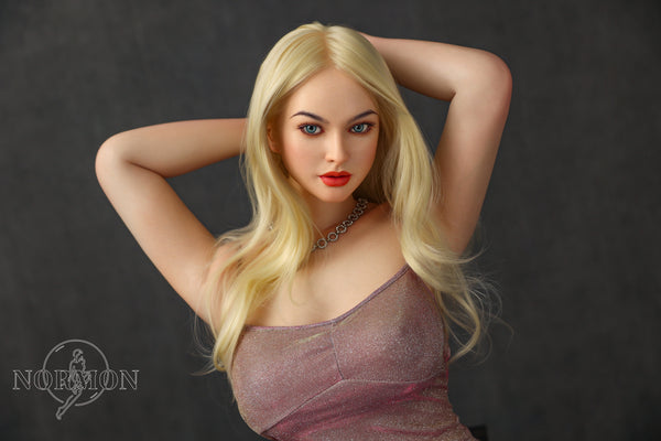A highly realistic beige sex doll with long blonde hair, posed in a pink dress. The doll has a lifelike appearance with detailed facial features and a flexible skeleton, designed for versatile posing.