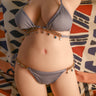 Person wearing a gray bikini with decorative accents on a patterned fabric background