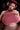 Person wearing a pink top with exaggerated cleavage in a dark setting