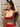 Woman wearing a red lace lingerie set with black cat ears against a stone wall.
